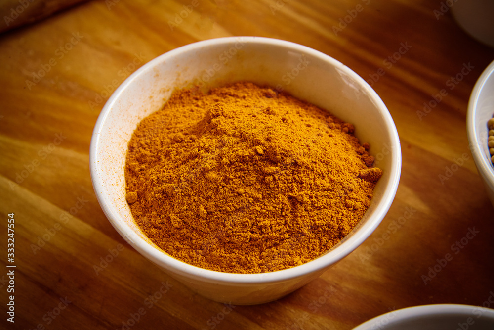 Turmeric powder in white bowl on wooden background Turmeric powder in white bowl on wooden background