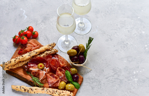 Traditional Italian appetizers antipasto : salami, bresaola, prosciutto parma, olives. Aperitif in Italy in Florence, Rome, aperitif in Milan. Two glasses of Prosecco and sticks of cereal bread