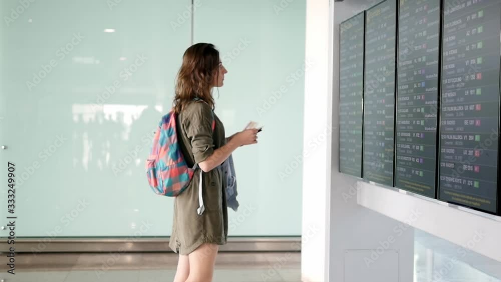 Woman at international airport near information board. The girl looks at the information board at the airport and is waiting for a flight home. Woman at international airport near information board. The girl looks at the information board at the airport and is waiting for a flight home.