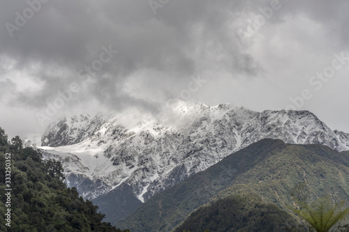 snow and peaks loom out of clouds at Franz Josef Waiau, West Coast, New Zealand