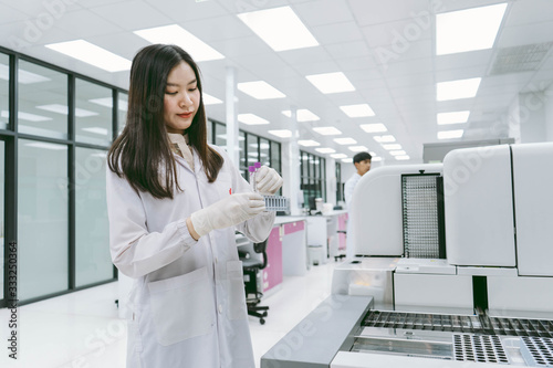 young female scientist working with automation blood analyzer in medical laboratory