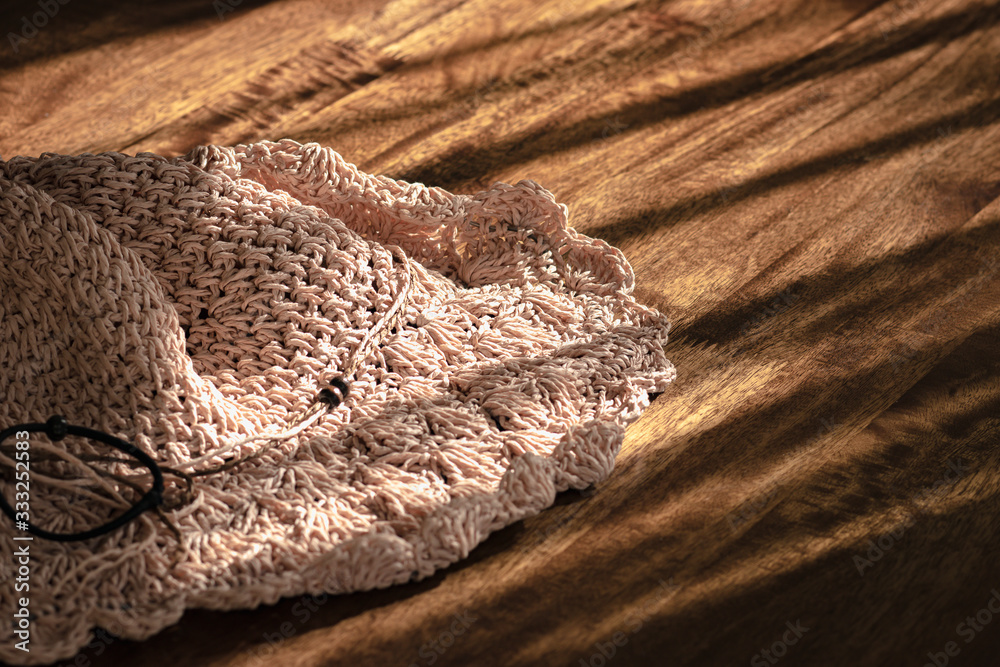 The wool hat placed on a wooden table that covering sunlight and shadow. The wool hat placed on a wooden table that covering sunlight and shadow.