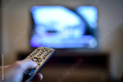 Stay at home concept photo with person holding a tv remote control zapping the news