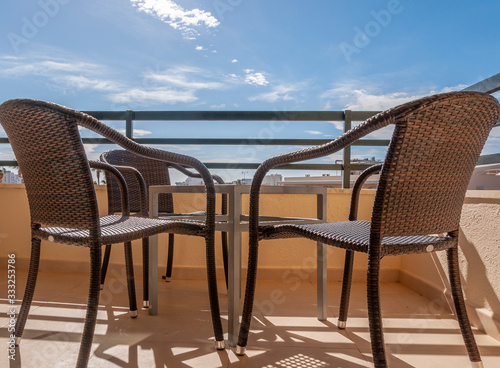 Sunny terrace with four dark chairs and a small metal table © Nemesio