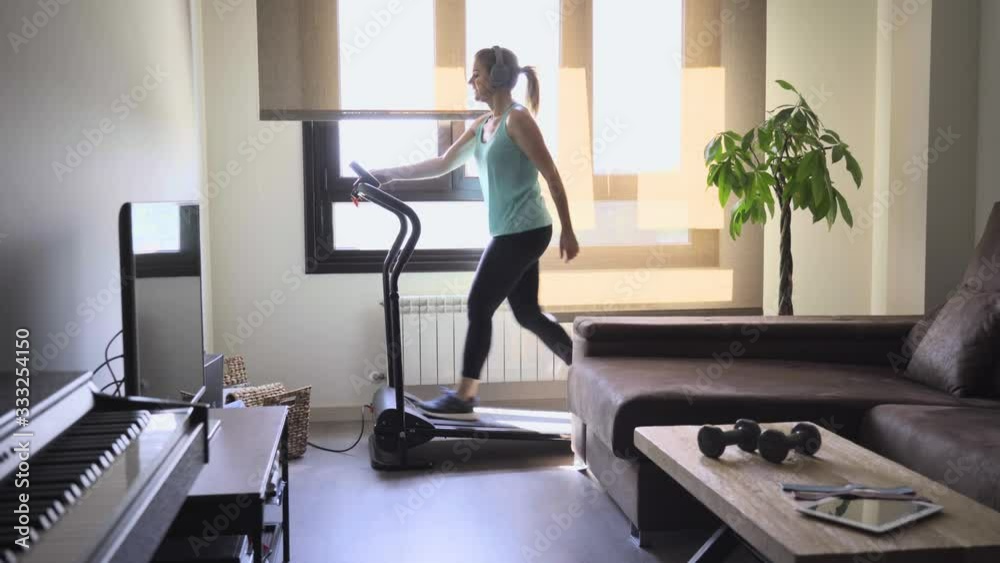 Woman exercises on a treadmill in her living room. Healthy life concept. Woman exercises on a treadmill in her living room. Healthy life concept.