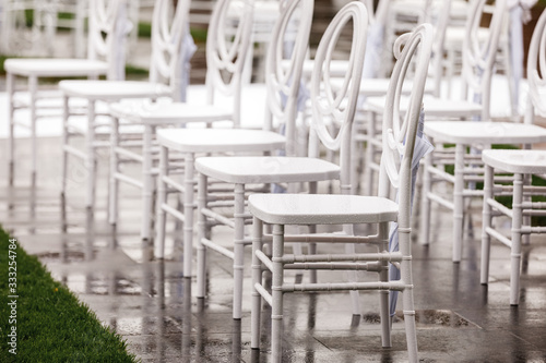 Rows of white empty wet chairs outdoors before a wedding ceremony. selective focus