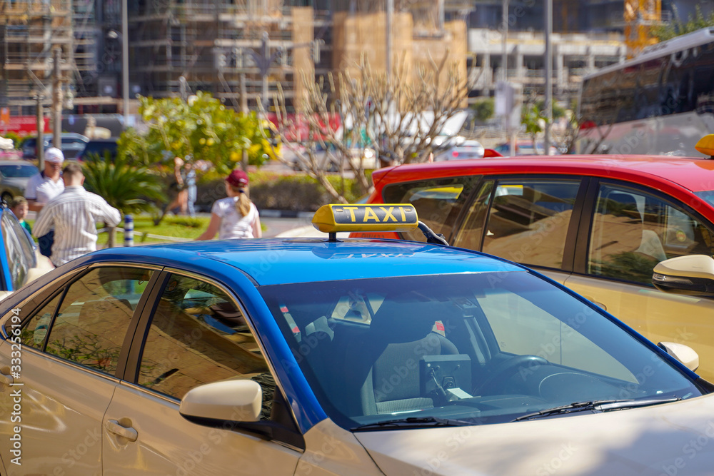 Picture of young man in cap and plaid shirt sitting in back seat in yellow taxi. Happy male getting into a cab. Businessman entering a taxi on city street