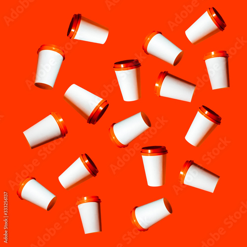 Pattern white cups with a red cap on an orange background.