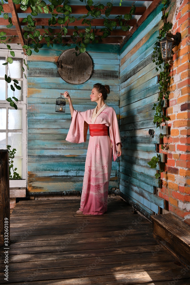 beautiful girl in a pink kimono with a cage with a bird