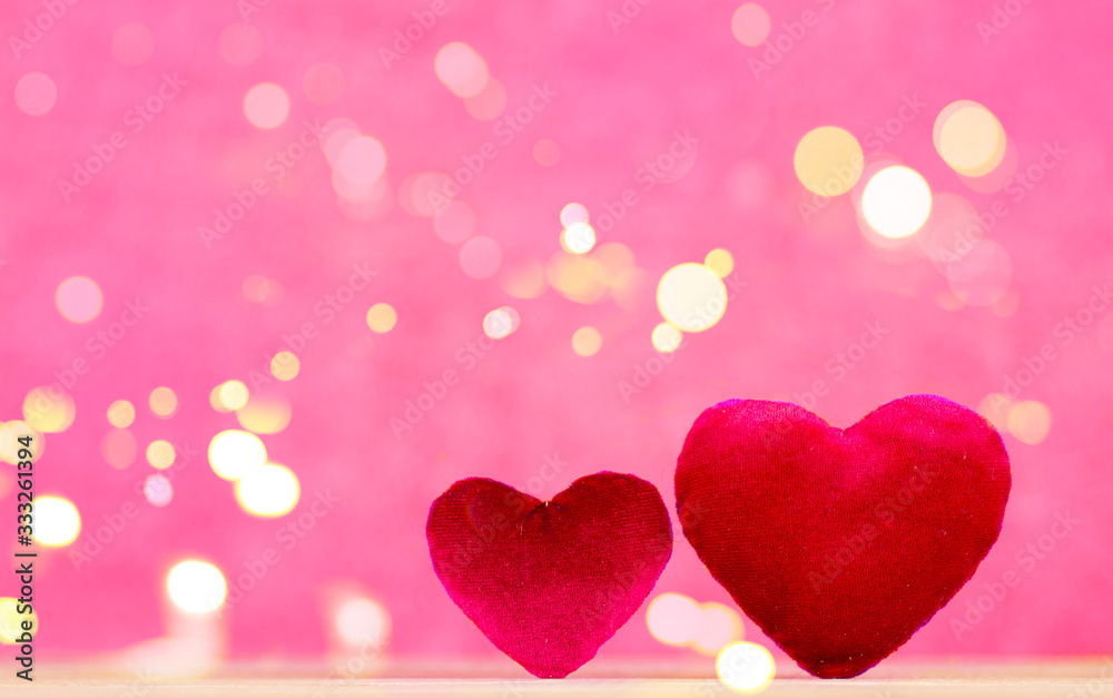 Closeup of two red hearts on wooden table against defocused bokeh lights.