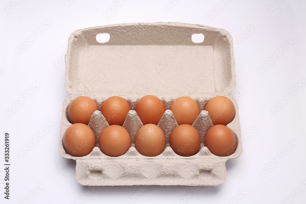 ten eggs lie in a cardboard box on a white background