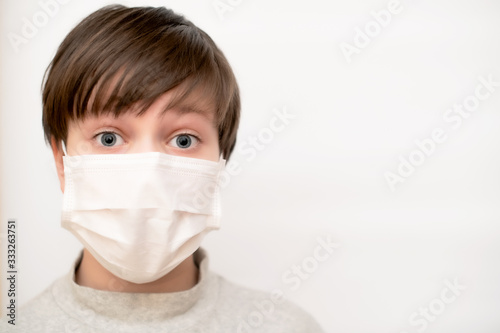 Boy close-up in a medical mask on a white background. The concept of protection, coronavirus and quarantine. Copy space.