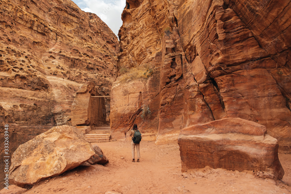 Lonely female backpacker tourist taking phtos in ancient mountain city of Petra, Jordan