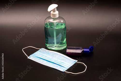 Turquoise antibacterial soap, antiseptic for hands and a medical mask on a black background