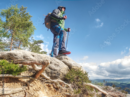Traveler in the mountains stands on a rock,