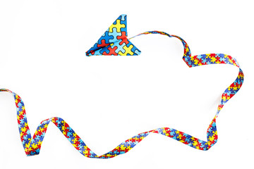 Autism awareness day or month. Paper plane in origami style with autism awareness puzzle ribbon on white background.