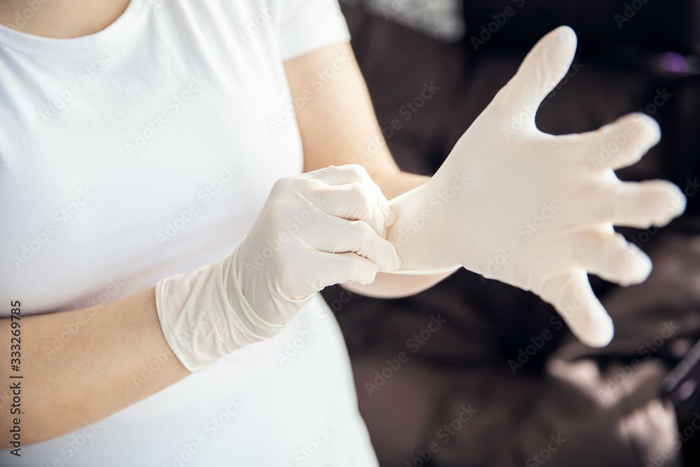 Woman puts on latex gloves that protects from microbes Woman puts on latex gloves that protects from microbes