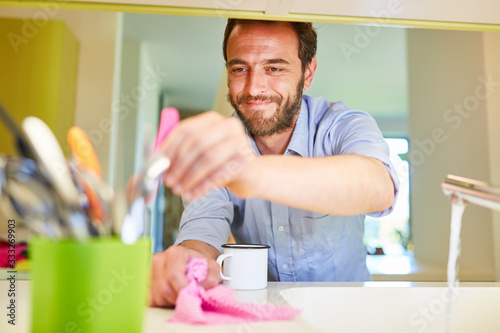 Smiling houseman while cleaning in the kitchen photo
