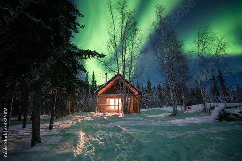 A cozy cabin with the warm light in the winter landscape under the northern lights, Yellowknife, Northwest Territories, Canada, North America