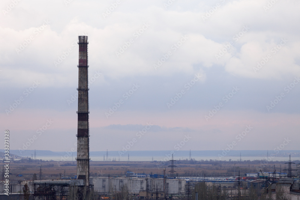 Industrial zone with a high chimney for the removal of smoke on the background of the lake.
