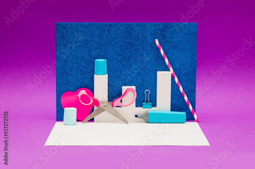 Scissors, marker and other decorations on a purple and shiny blue background photo