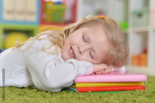 Cute little girl sleeping on pile of books