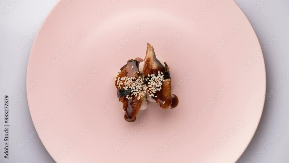 Top view of spinning two eel nigiri sushi spinning pink plate. Top view of spinning two eel nigiri sushi spinning pink plate.