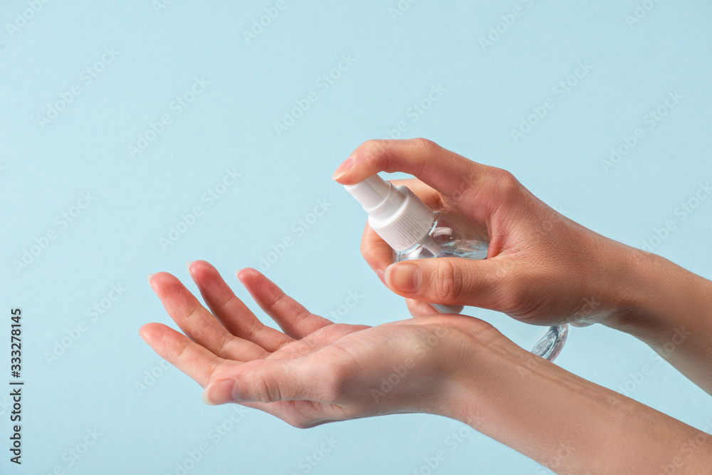 cropped view of woman holding spray bottle with hand sanitizer isolated on blue cropped view of woman holding spray bottle with hand sanitizer isolated on blue