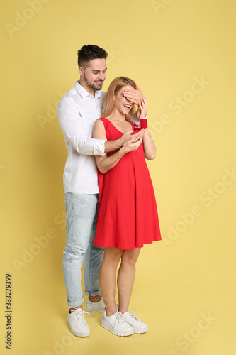 Man with engagement ring making marriage proposal to girlfriend on yellow background © New Africa