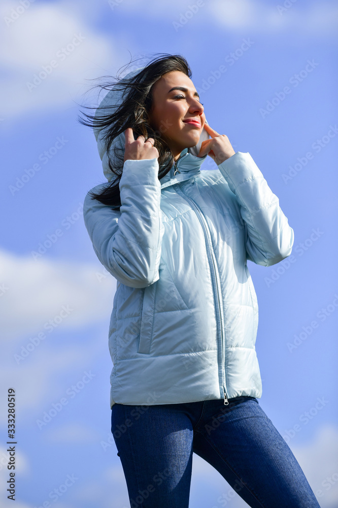 girl wearing casual jeans clothes. enjoys sunny day and blue sky. beauty and fashion. girl wear jacket in city street. Stylish fashion model outdoor. People freedom style. Winter Warm Clothing