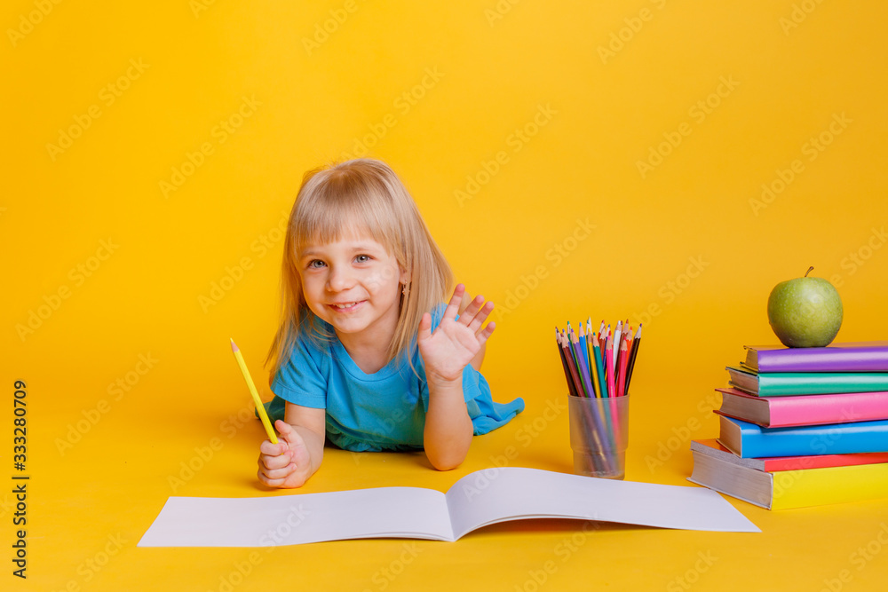 child girl draws colored pencils on a yellow background. Concept of preschool education child girl draws colored pencils on a yellow background. Concept of preschool education