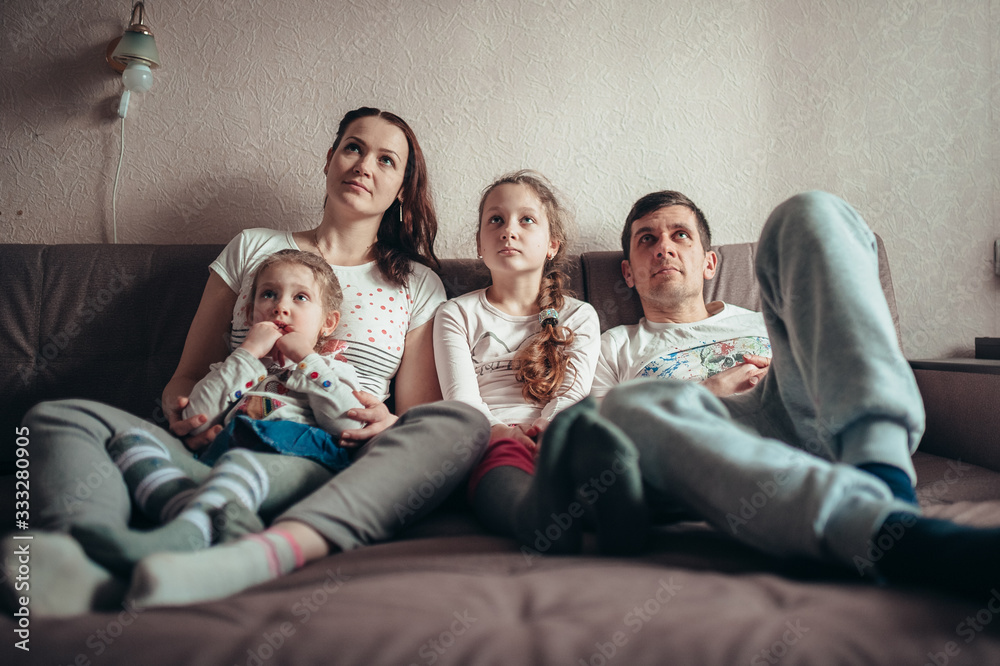 The family is sitting on the couch and watching TV The family is sitting on the couch and watching TV
