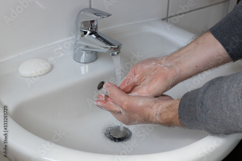 Detail of a Young male washing his Hands with Soap under running water in order to reduce infection Risk during corona Virus pandemic