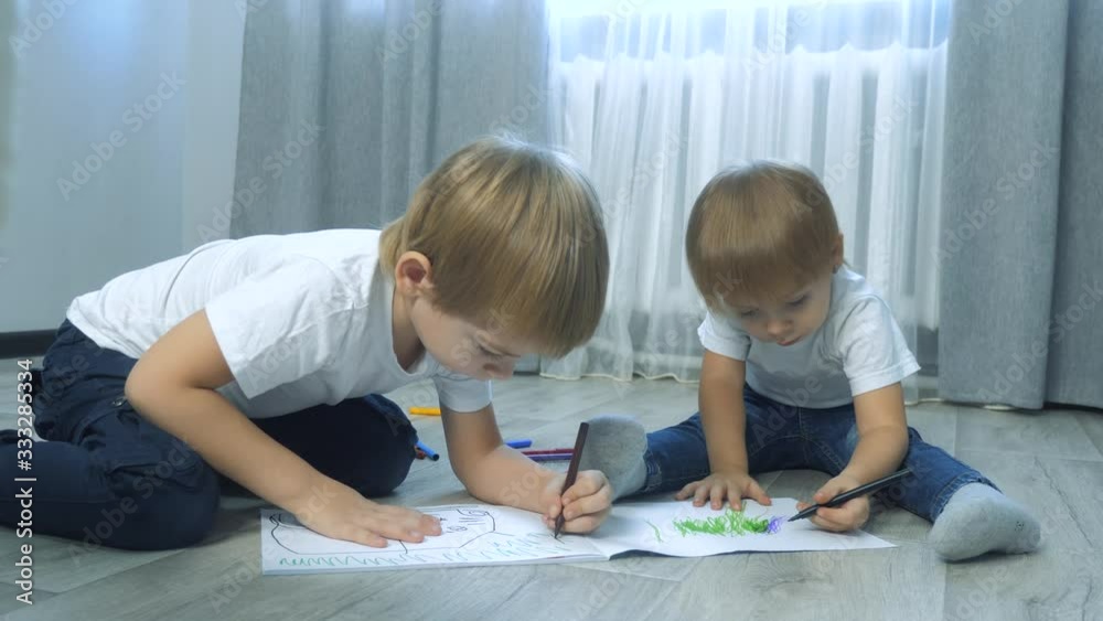 children draw with felt-tip pens in an album. little boy and girl concept childhood brother and sister play paint on lifestyle the floor with colored markers children draw with felt-tip pens in an album. little boy and girl concept childhood brother and sister play paint on lifestyle the floor with colored markers