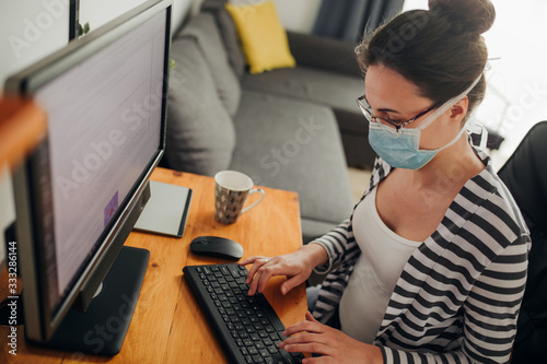 Young woman working on computer at her home office. Home office during isolation time photo