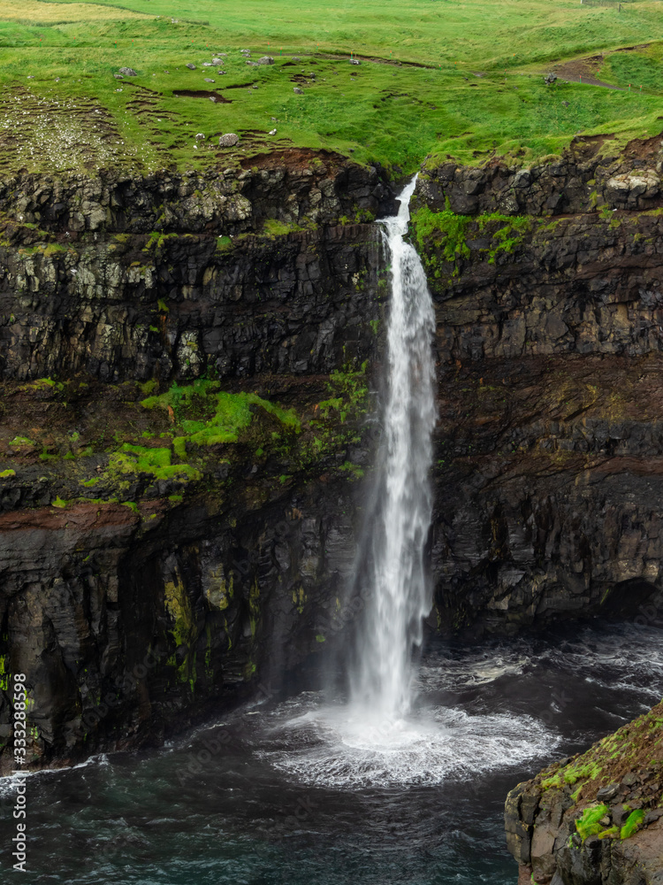 Obraz premium Faroe Islands. Múlafossur Waterfall. Vertical. Long exposure.