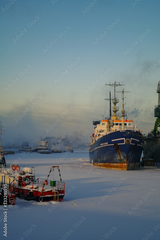 Obraz premium Ships and cranes in cargo port of St. Petersburg in winter time, covered by ice and snow