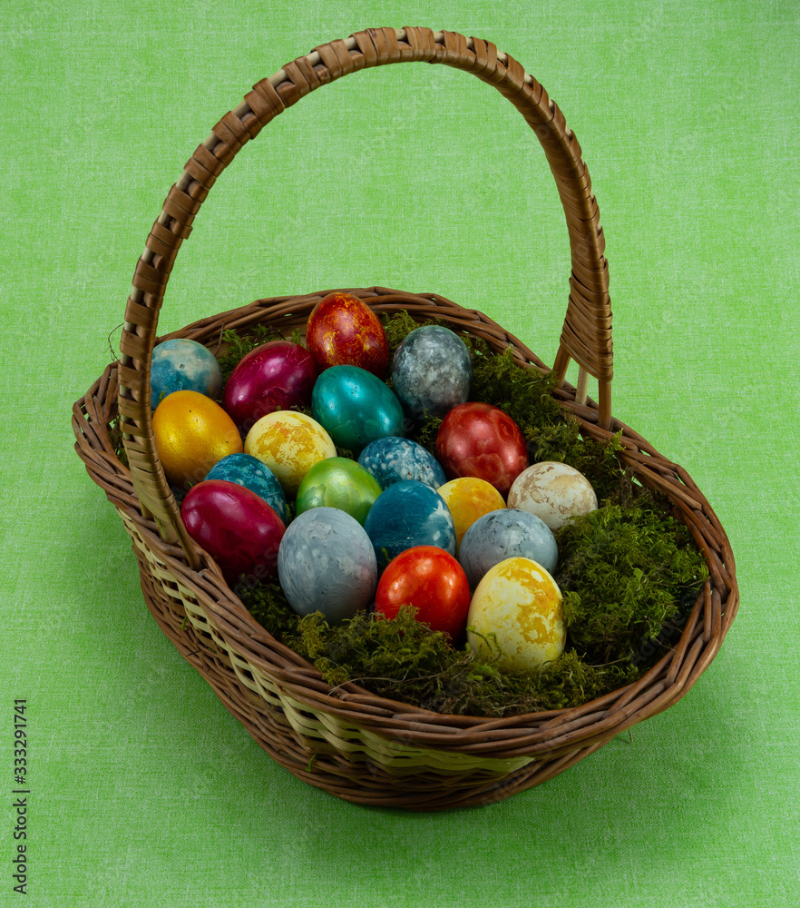 Easter, colored painted eggs in a wicker basket with moss Easter, colored painted eggs in a wicker basket with moss