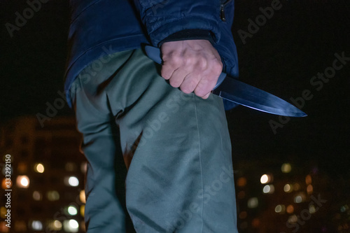 man with a knife in his hands at night on the street close-up. Concept of crimes, robbery