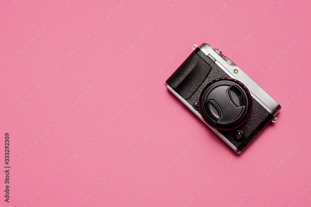 Vintage retro mirrorless camera with lens and lens cap shot from above on a pastel pink