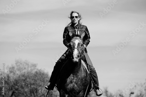 Western lifestyle image shows woman riding horse in black and white, rural scenic adventure.