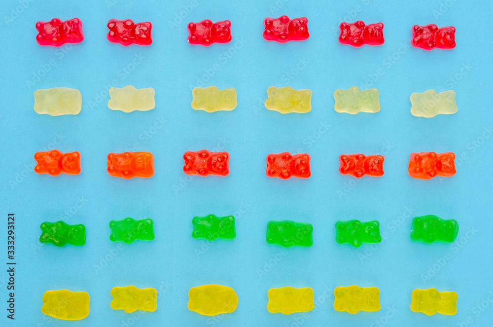 Delicious bright colored jelly bears on a blue background laid out in the same order, top view Delicious bright colored jelly bears on a blue background laid out in the same order, top view