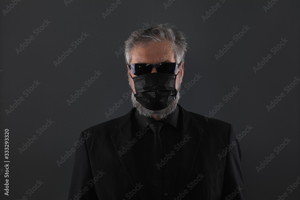 Fototapeta premium close-up studio portrait of a man in a black medical mask from coronavirus on a black background