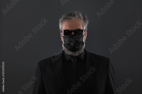 close-up studio portrait of a man in a black medical mask from coronavirus on a black background © serikbaib