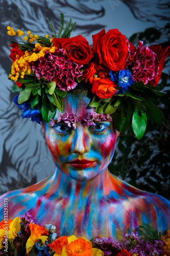 Fototapeta Naklejka Na Ścianę i Meble -  Portrait of a girl whose face is painted with colored paints in a wreath of flowers. In Frida Kahlo's footsteps