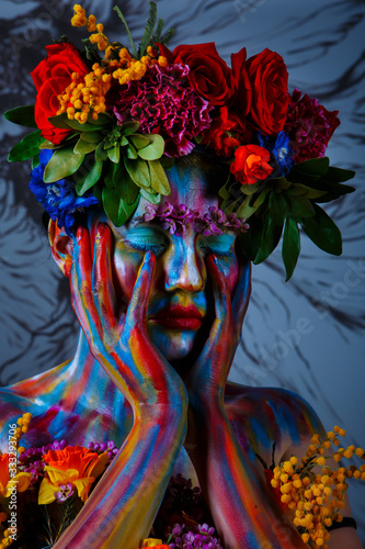 Portrait of a girl whose face is painted with colored paints in a wreath of flowers. In Frida Kahlo's footsteps photo