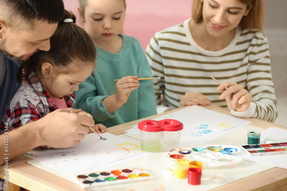 Lovely family painting at table indoors. Playing with children Lovely family painting at table indoors. Playing with children
