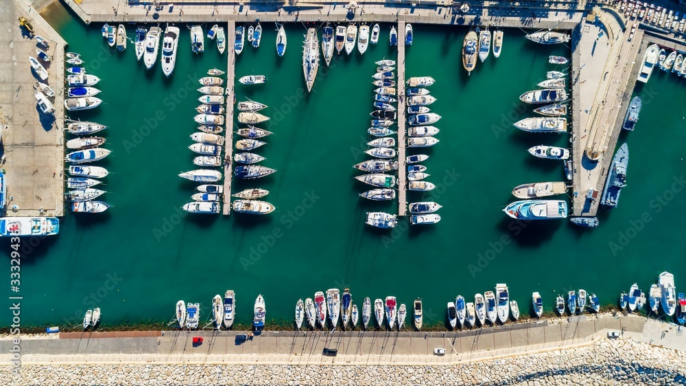 Aerial bird's eye view of Latchi port, Akamas peninsula, Polis Chrysochous, Paphos, Cyprus. The Latsi harbour with boats and yachts aligned, fish restaurants, promenade, beach tourist area from above.