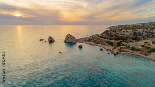 Aerial Bird's eye view of Petra tou Romiou, aka Aphrodite's rock a famous tourist travel destination landmark in Paphos, Cyprus. The sea bay of goddess Afroditi birthplace at sunset from above. photo
