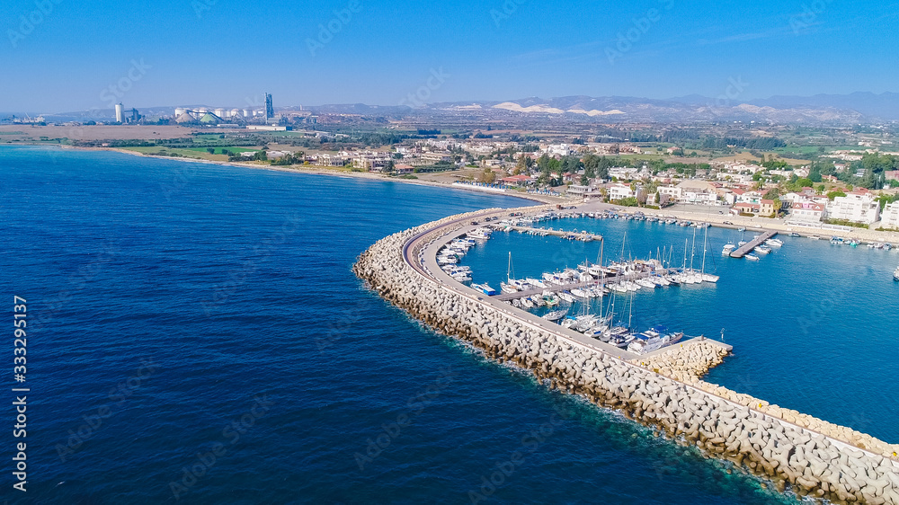 Aerial bird's eye view of Zygi fishing village port, Larnaca, Cyprus. The fish boats moored in the harbour with docked yachts and skyline of the town near Limassol from above.